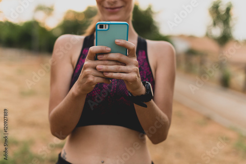 Sportswoman using her cell phone in park after workout photo