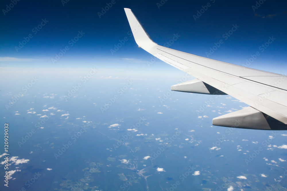 Naklejka premium Airplane wing during flight over the blue sky