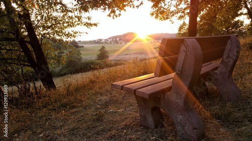 Photos Sonnenuntergang an einer leeren Bank in der Natur