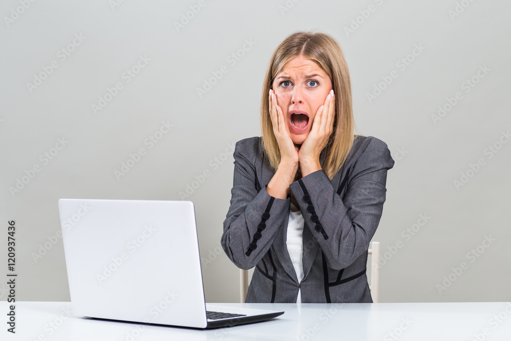 Businesswoman with laptop sitting at the table and she is in panic.
Businesswoman with laptop sitting at the table and she is in panic.