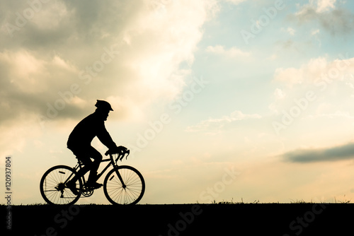 Silhouette of cyclist motion on sunset background