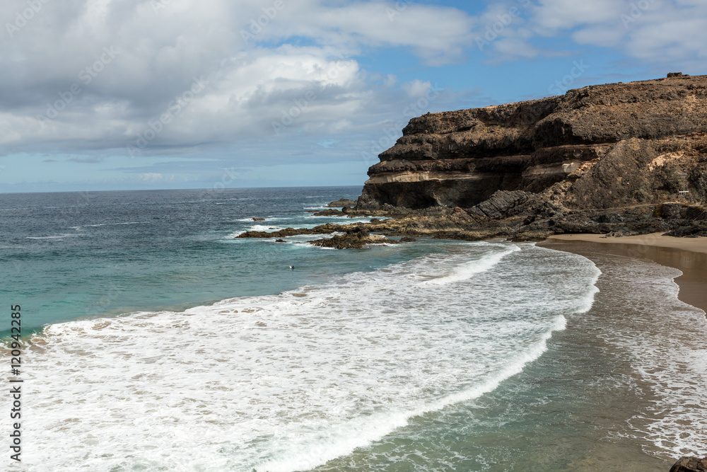 Wave splashing over a rock on the beach of Puertito de los Molinos on Fuerteventura. Canary Island, Spain