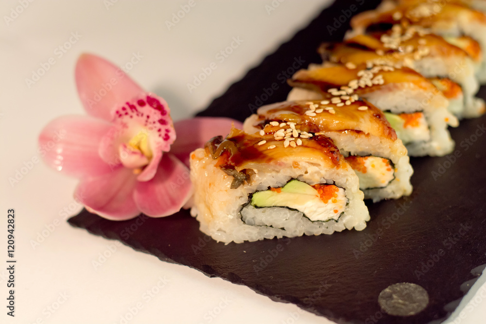 Eel sushi roll, decorated with sesame, on slate texture close up Eel sushi roll, decorated with sesame, on slate texture close up