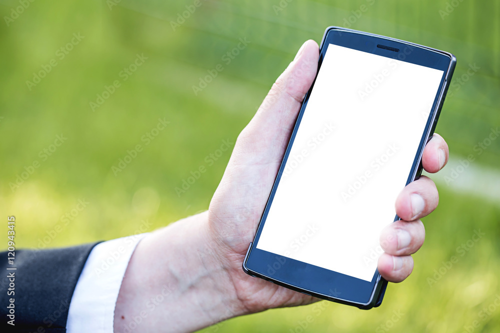 Smart phone with blank space on Hand of Caucasian Business Man holding Cellphone over Blurred garden outdoor background. Image for Advertising online Application Solution or Mobile banking Concept.