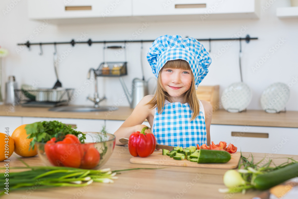 Portrait of a pretty little girl in cook clothes on a kitchen Portrait of a pretty little girl in cook clothes on a kitchen
