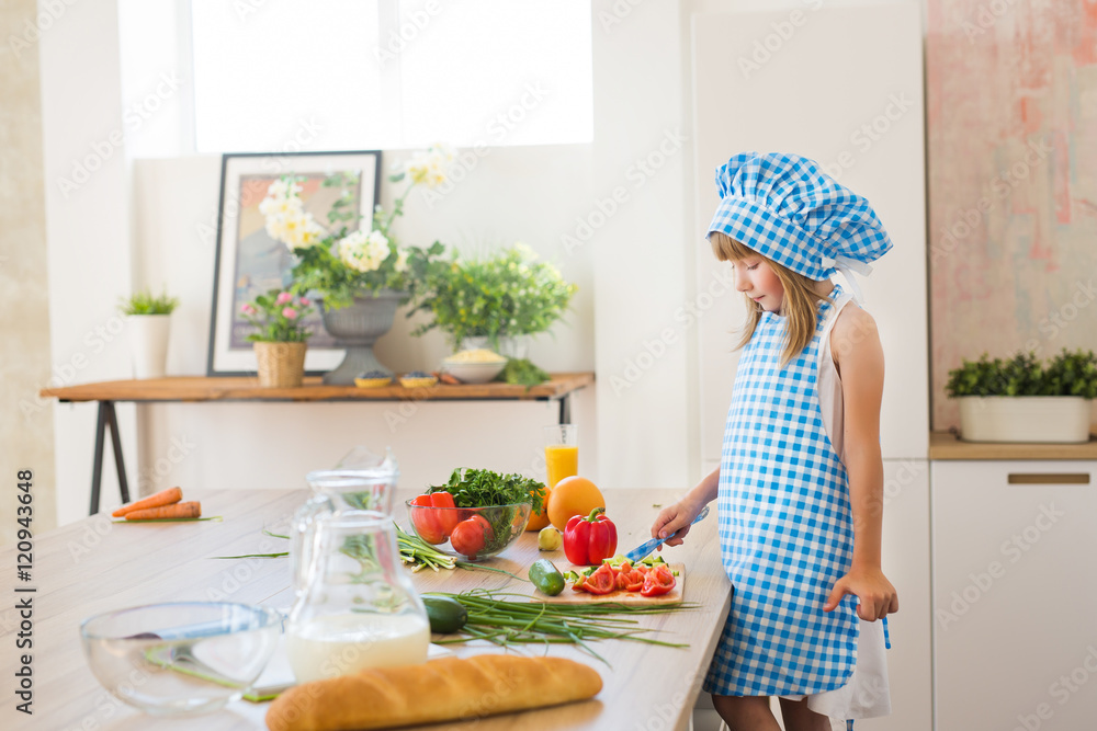 Pretty little girl in cook clothes thinks on a kitchen Pretty little girl in cook clothes thinks on a kitchen