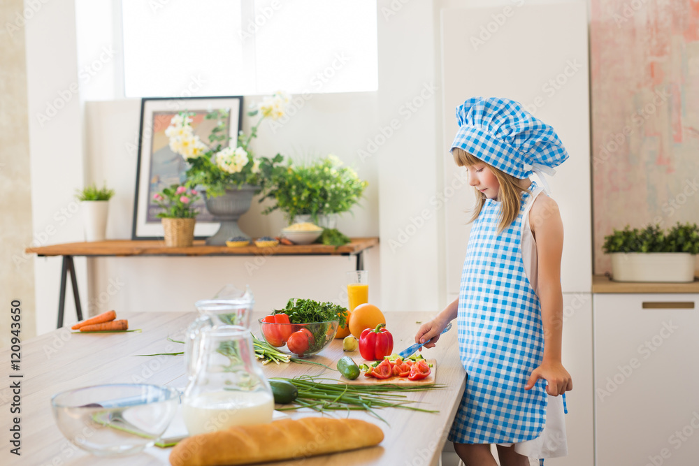 Pretty little girl in cook clothes thinks on a kitchen Pretty little girl in cook clothes thinks on a kitchen