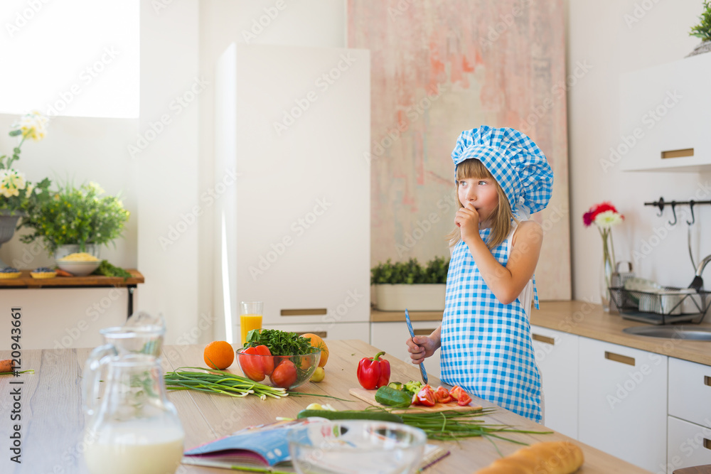 Pretty little girl in cook clothes found an idea on a kitchen Pretty little girl in cook clothes found an idea on a kitchen