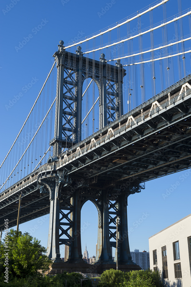 Close up of the Brooklyn tower of the Manhattan Bridge from the greenery in the park in DUMBO (Down Under the Manhattan Bridge Overpass) in New York City