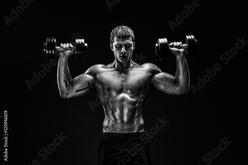 Handsome bodybuilder doing exercise with dumbbell. Isolated. photo