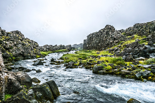 Beautiful summer brook with huge grey rocks and bright grass in Iceland