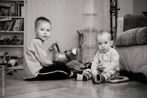 Два мальчика сидят дома на полу чб photo