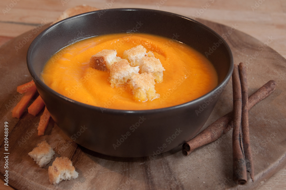Pumpkin soup in a brown bowl on dark wood Pumpkin soup in a brown bowl on dark wood
