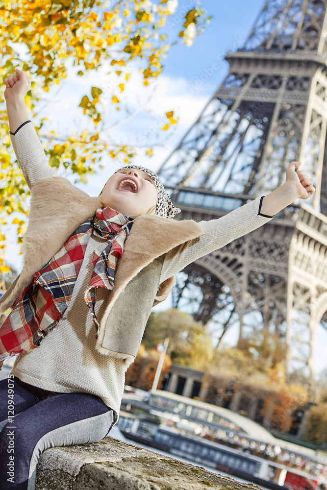 smiling elegant child on embankment in Paris, France rejoicing