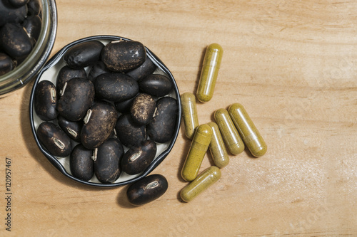 The seeds of Velvet bean or Mucuna pruriens and Pill capsules that contain herbal medicine powder have been used for traditional medicine, selective focused, on wooden background with copy space