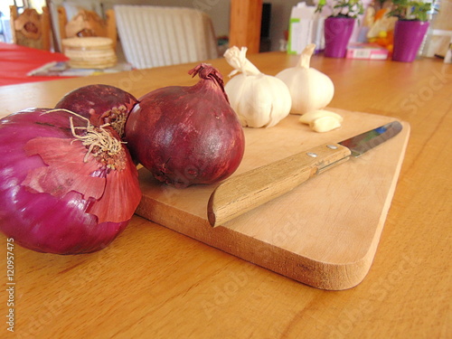 garlic and onion laying on a cutting board with a knife photo