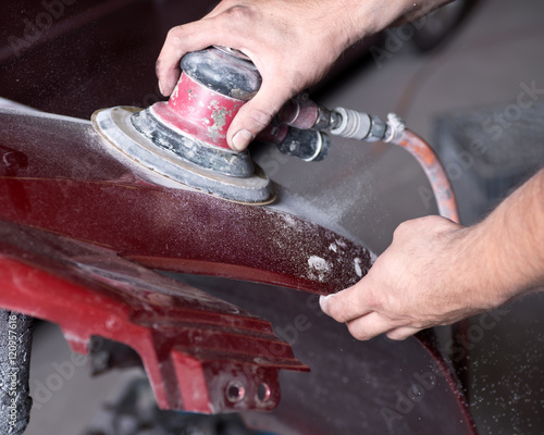 Foto Worker is sanding filler with air sander in auto body shop