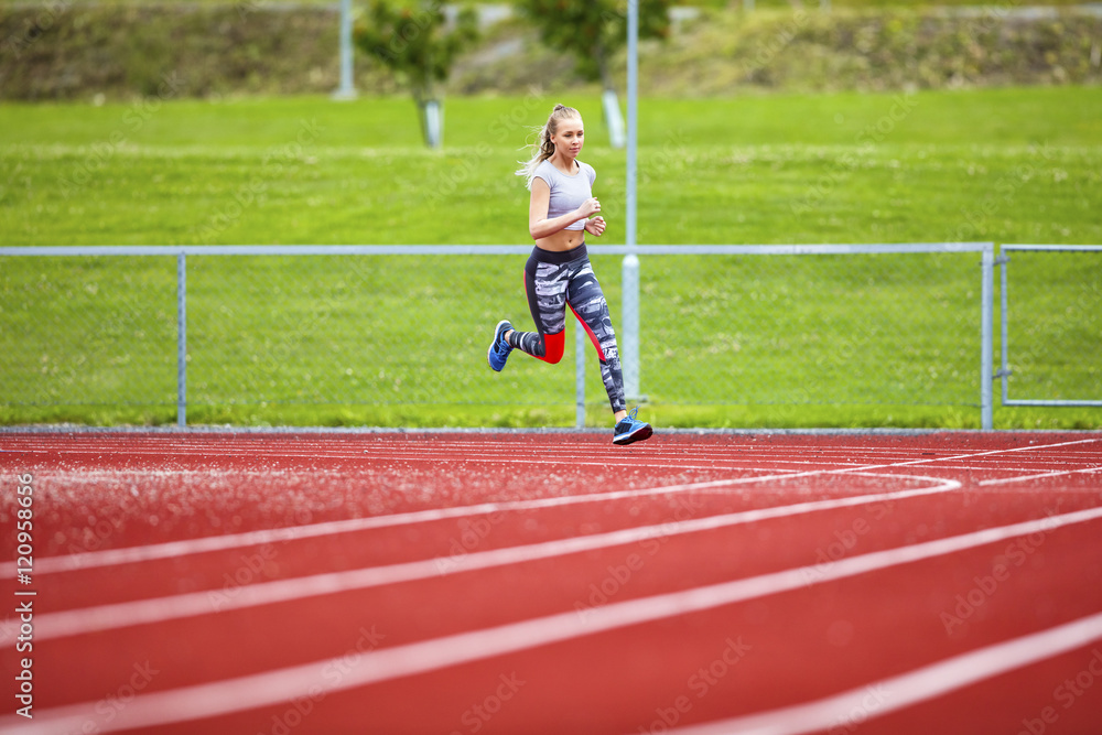 Obraz premium Determined Young Woman Running On Sports Tracks