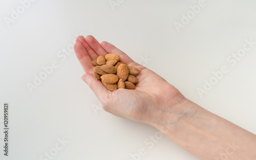 Woman Holding Almonds in Her Hand on a White Background
