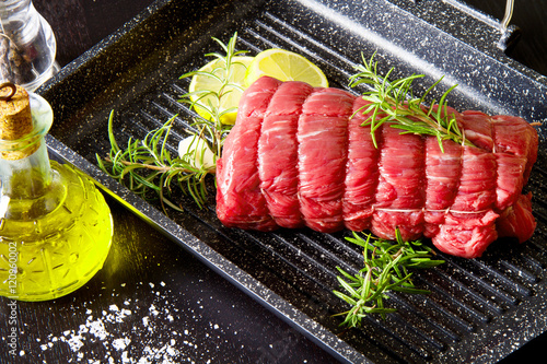 Fotografie roast of beef with rosemary on plate pot on black