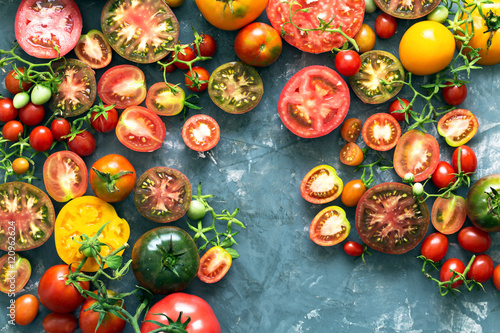 A lot of fresh and ripe tomatoes of different sizes and colours  – top view with copy space