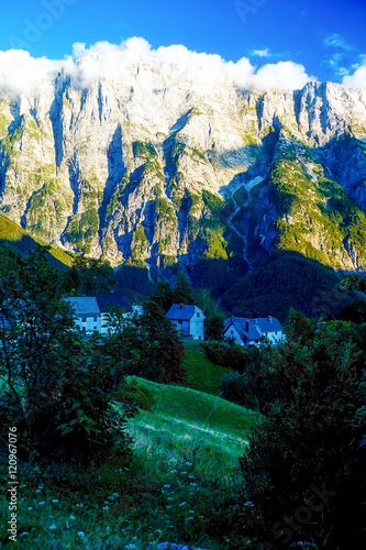 beautiful alpine mountain landscape on summer day with little village in the valley