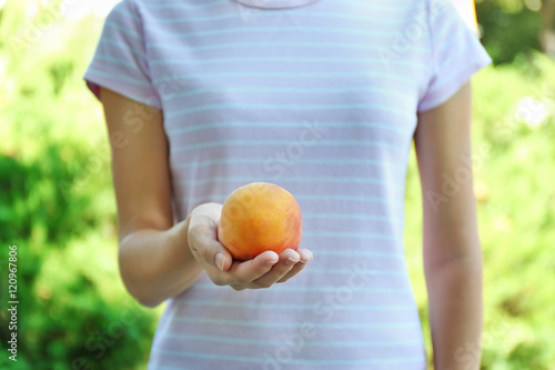 Woman holding peach on blurred nature background