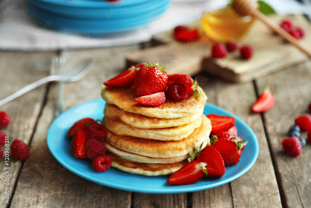 Tasty pancakes with fresh berries on plate on wooden background Tasty pancakes with fresh berries on plate on wooden background