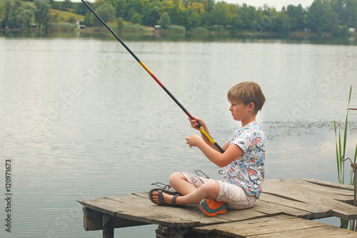Boy with a fishing rod on the lake