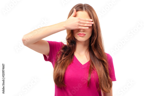 See nothing. Beautiful young long hair woman standing against white background and covering eyes with hand