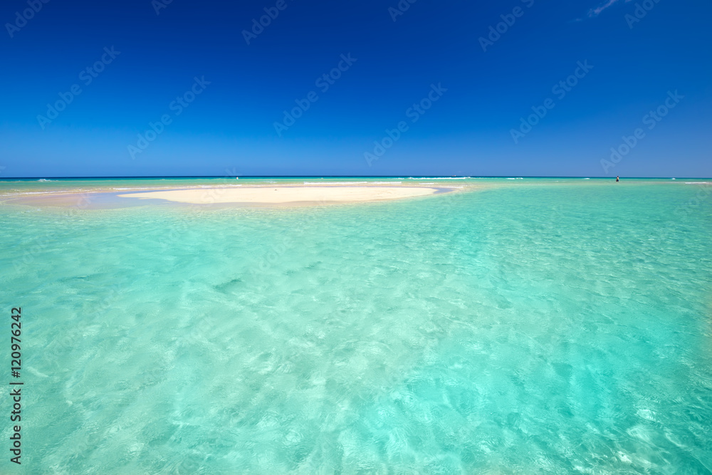Island with sandy beach, green lagoon and clear water.