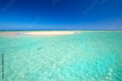 Island with sandy beach, green lagoon and clear water.