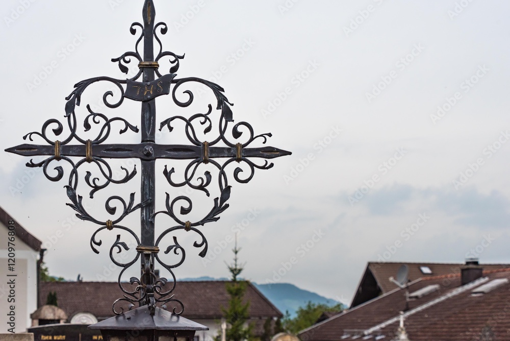 Schmiedeeisernes Grabkreuz vor grauem Himmel Schmiedeeisernes Grabkreuz vor grauem Himmel