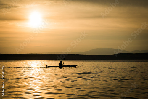 Sunset Landscape with Silhouette Boat. Man crossing with a boat. © icephotography