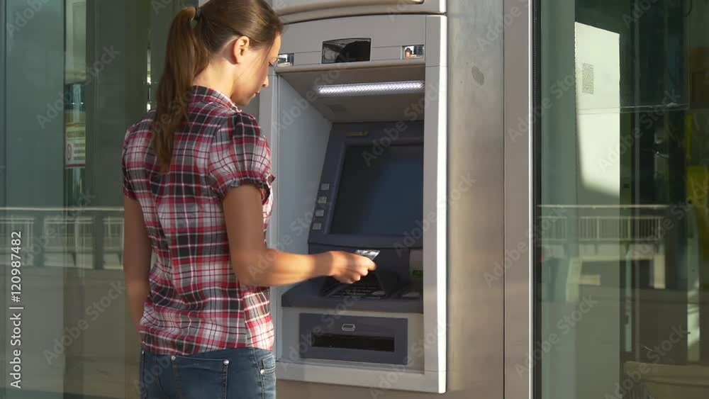 Woman inserts banking card in ATM Woman inserts banking card in ATM