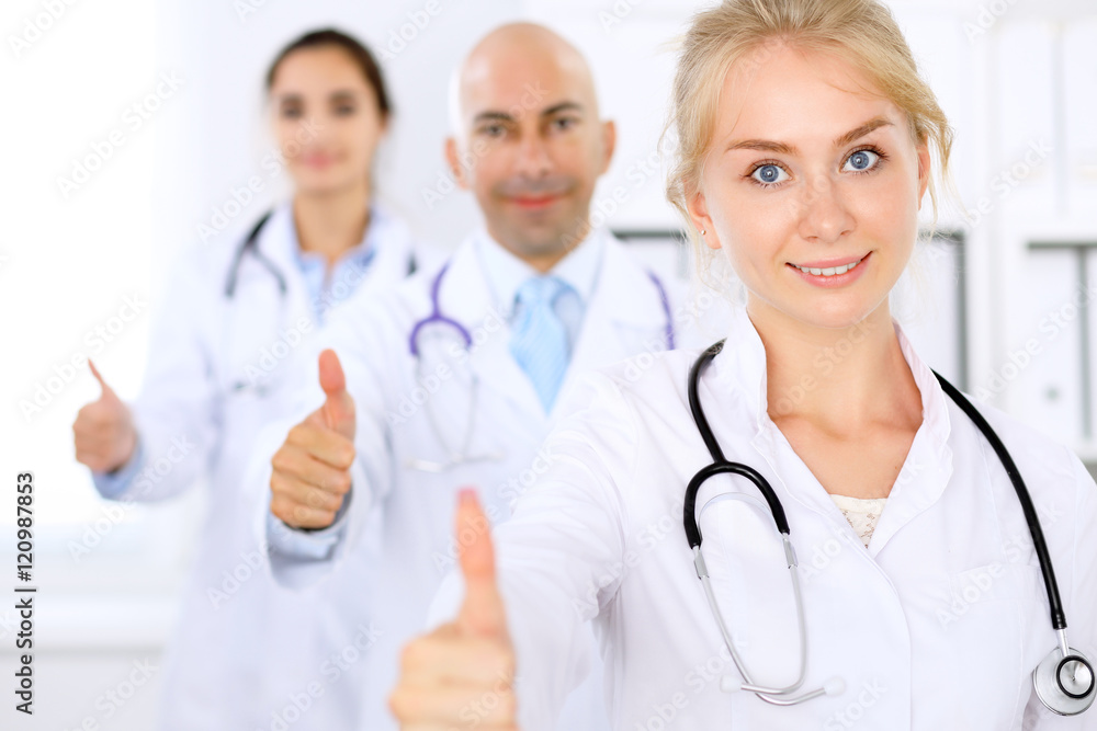 Happy doctor woman with medical staff at the hospital. Thumbs up! Happy doctor woman with medical staff at the hospital. Thumbs up!