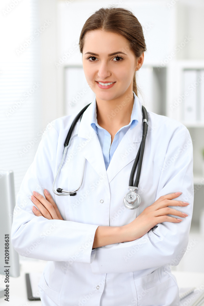 Young brunette female doctor standing with clipboard and smiling at hospital. Physician ready to examine patient Young brunette female doctor standing with clipboard and smiling at hospital. Physician ready to examine patient