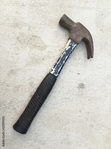 Old and rusty hammer on cement background photo