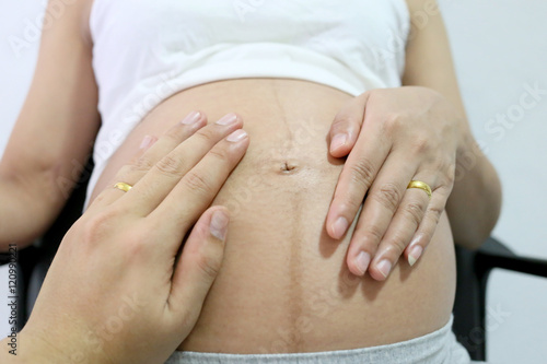 Pregnant women hand and husband hand placed on belly.