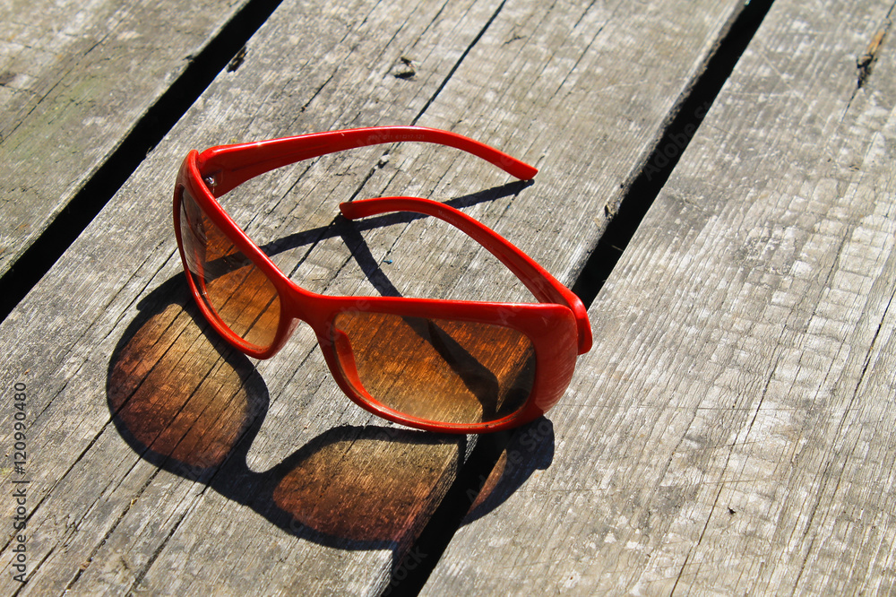 Red sunglasses on wooden background