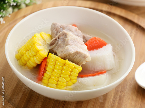 Corn and carrots yam stew with pork ribs in white bowl on wooden photo