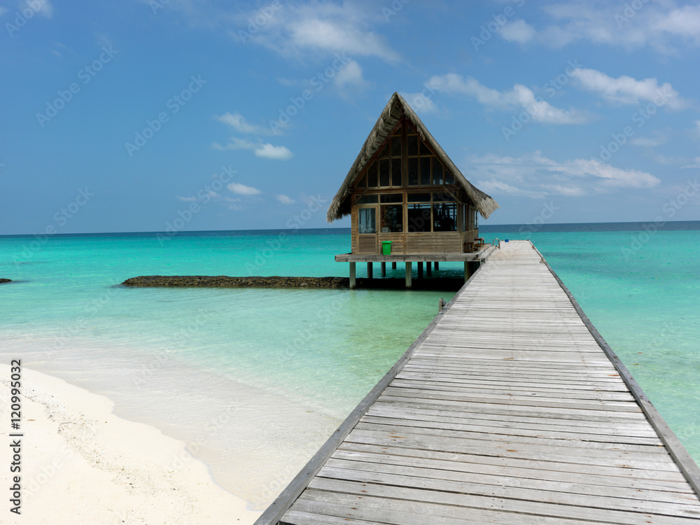 Maldives. A footpath goes to the bungalow, which is in the ocean. Sunny day.