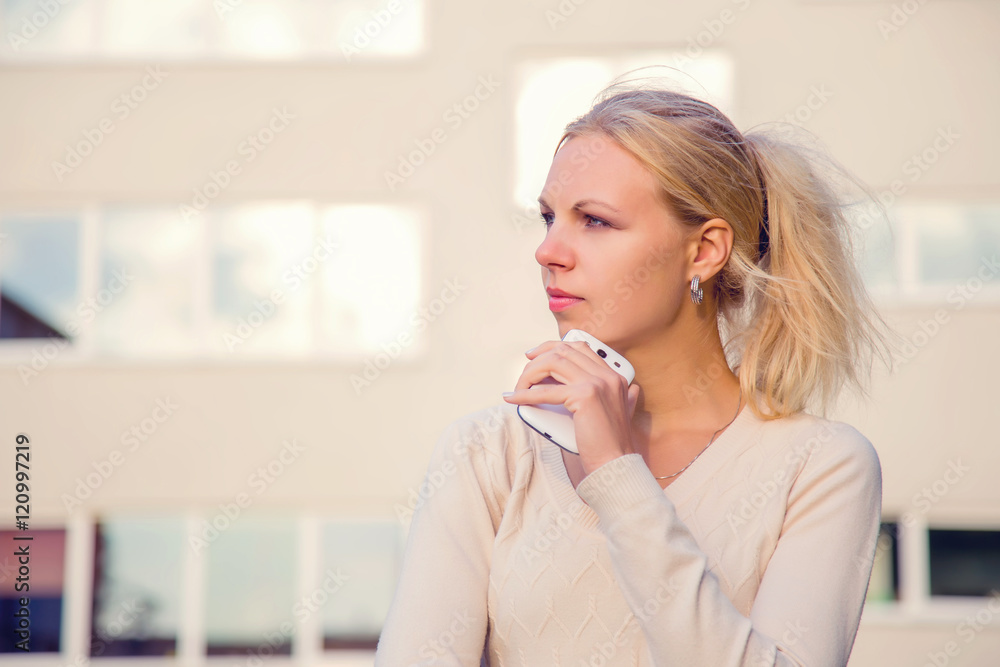 Young woman standing in front of the building and waiting for a call from a working partner Young woman standing in front of the building and waiting for a call from a working partner
