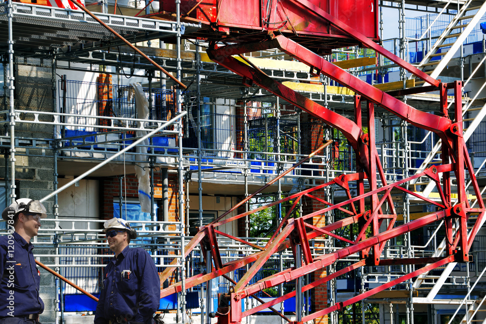 two construction workers with giant scaffoldings in background two construction workers with giant scaffoldings in background
