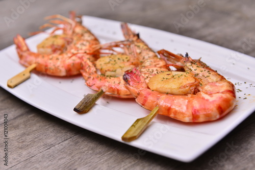Fried shrimp scallops string skewers on white plate on wooden ta