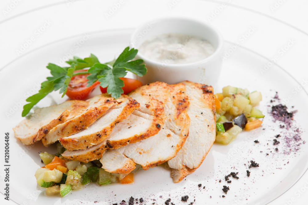 Roasted chicken breast with ratatouille and herbs on white plate