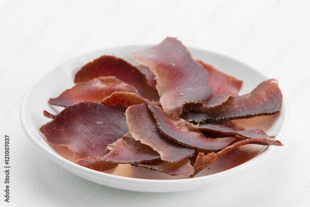 Sliced dried beef meat jerky on white plate Sliced dried beef meat jerky on white plate