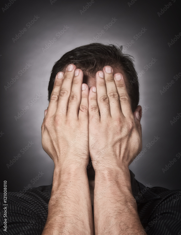Studio portrait of a stressed Caucasian man covering his face with the hands Studio portrait of a stressed Caucasian man covering his face with the hands