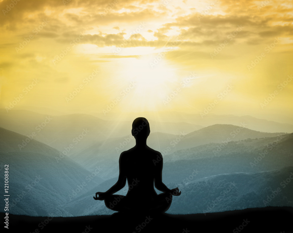 Yoga silhouette on the mountain in rays of the dawn