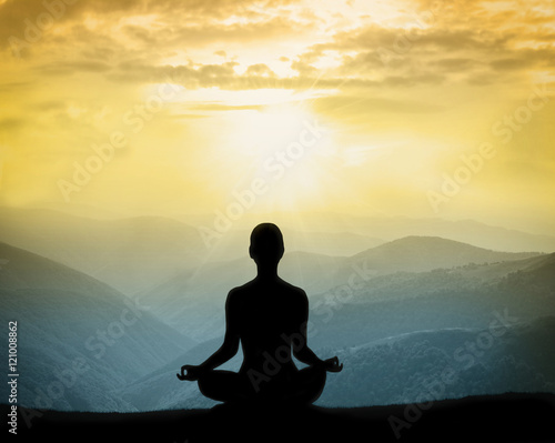 Yoga silhouette on the mountain in rays of the dawn